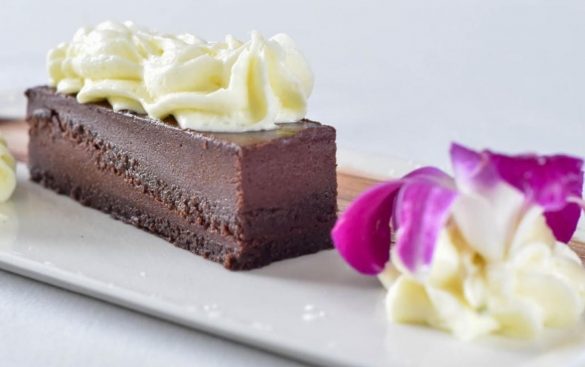 chocolate fudge cake with whipped cream and edible flower at Pescada Dairy