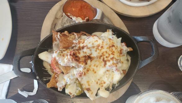 nachos kalamata olives, bechamel sauce, green chilli, cheese, tomato dip at Upper Crust Queens